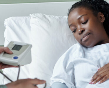 Black pregnant woman in hospital bed being checked by doctor
