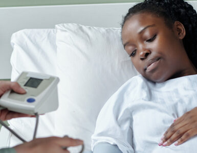 Black pregnant woman in hospital bed being checked by doctor