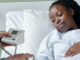 Black pregnant woman in hospital bed being checked by doctor