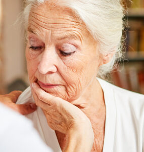 Elderly woman looking concerned while talking to her care provider.