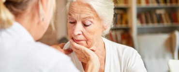Elderly woman looking concerned while talking to her care provider.