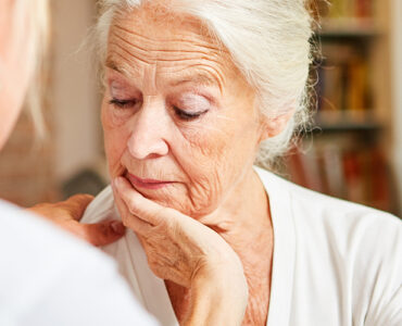 Elderly woman looking concerned while talking to her care provider.
