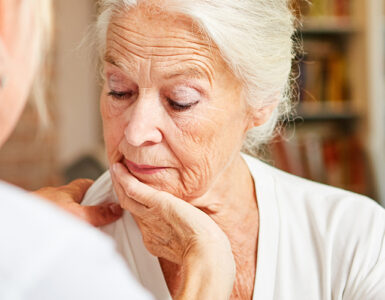 Elderly woman looking concerned while talking to her care provider.