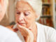 Elderly woman looking concerned while talking to her care provider.