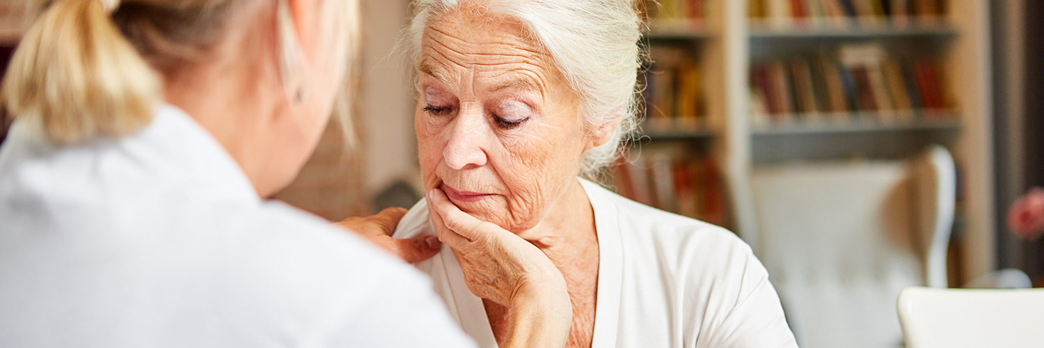 Elderly woman looking concerned while talking to her care provider.
