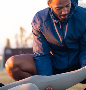 Sports therapist massaging the leg of a female athlete outdoors