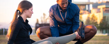 Sports therapist massaging the leg of a female athlete outdoors
