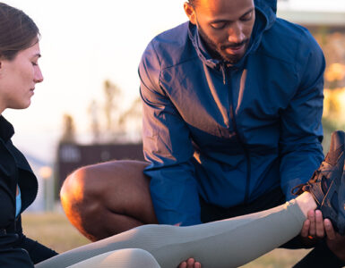 Sports therapist massaging the leg of a female athlete outdoors