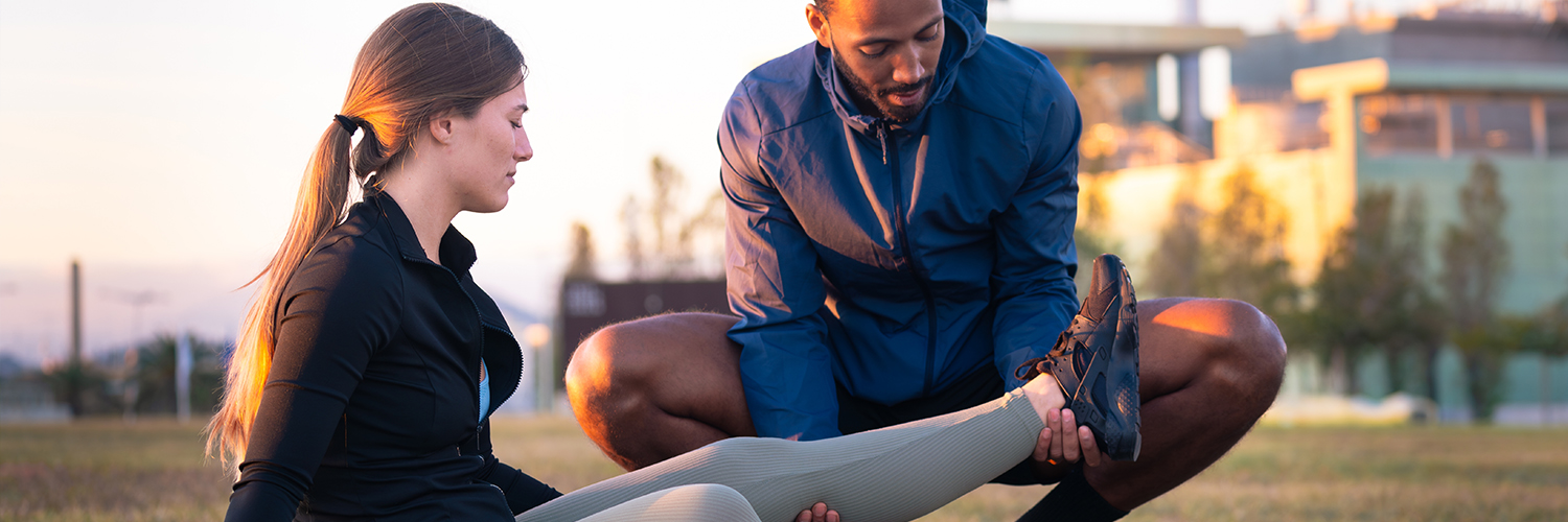Sports therapist massaging the leg of a female athlete outdoors