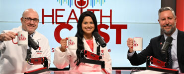 Three doctors in the Stony Brook Medicine studio holding their Healthcast-branded mugs in the air.