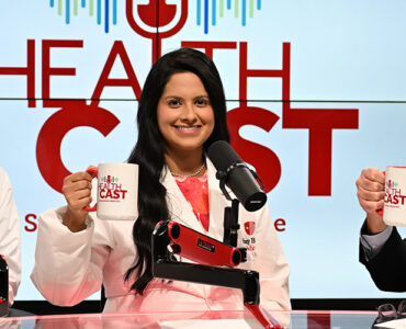 Three doctors in the Stony Brook Medicine studio holding their Healthcast-branded mugs in the air.