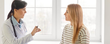 Supporting caring female doctor consulting young woman patient