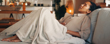 Woman on the couch with a stomach ache.