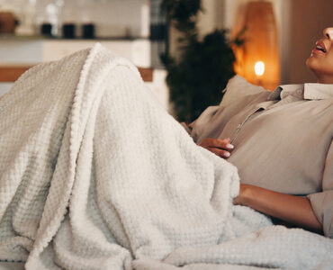 Woman on the couch with a stomach ache.