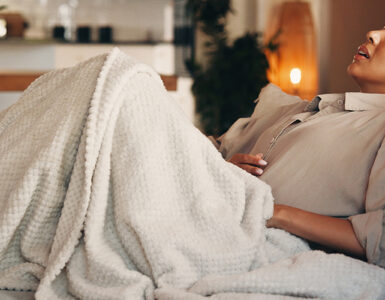 Woman on the couch with a stomach ache.