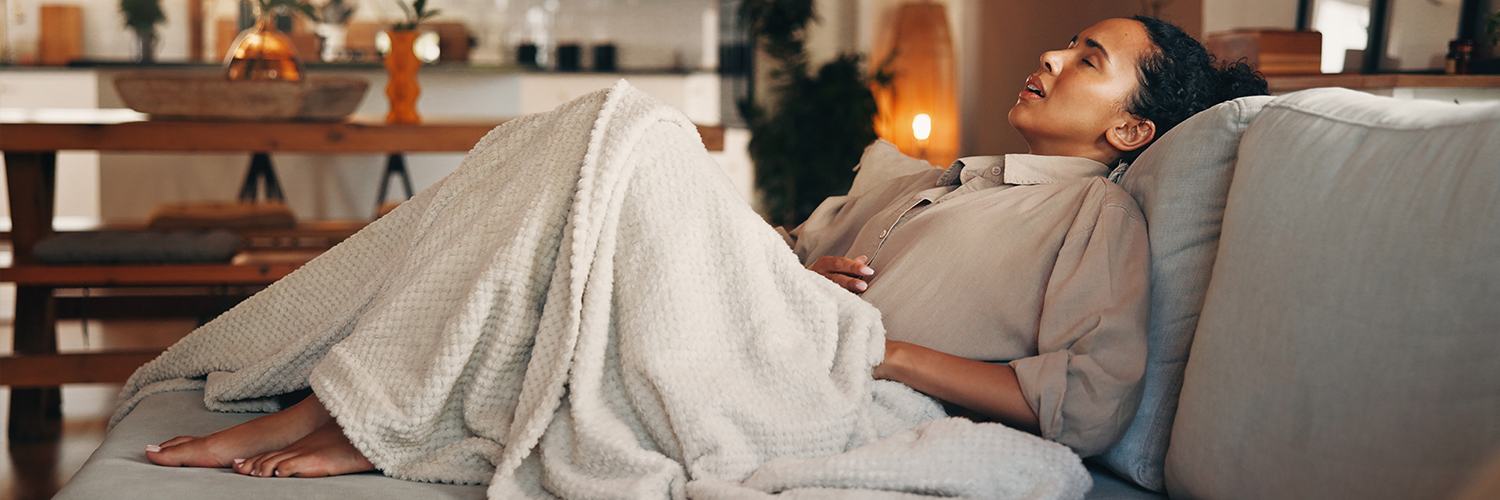 Woman on the couch with a stomach ache.