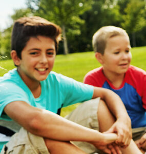 Kids sitting on lawn, smiling.