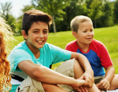 Kids sitting on lawn, smiling.