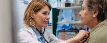 Doctor checking elderly female patient's heart.