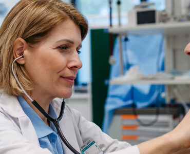 Doctor checking elderly female patient's heart.