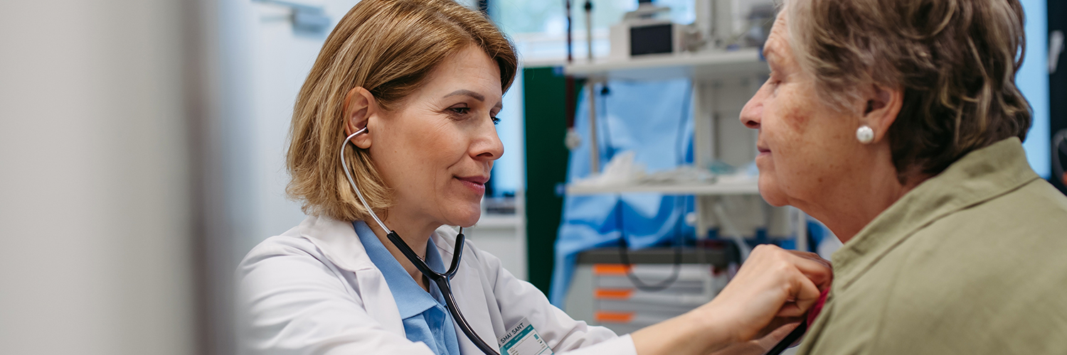 Doctor checking elderly female patient's heart.