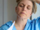 Menopausal Mature Woman Having Hot Flashes At Home Cooling Herself With Letters Or Documents