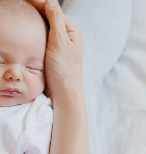 Sleeping newborn in hands of his mother.