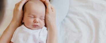Sleeping newborn in hands of his mother.