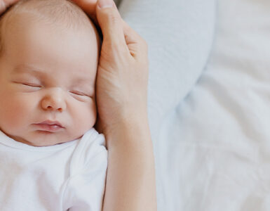 Sleeping newborn in hands of his mother.