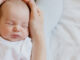 Sleeping newborn in hands of his mother.