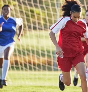 Sports team, girl soccer and kick ball on field in a tournament.