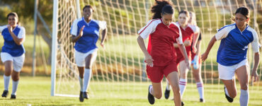 Sports team, girl soccer and kick ball on field in a tournament.