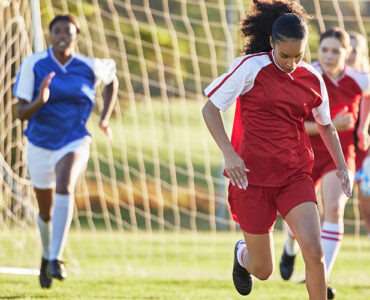 Sports team, girl soccer and kick ball on field in a tournament.