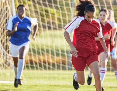 Sports team, girl soccer and kick ball on field in a tournament.