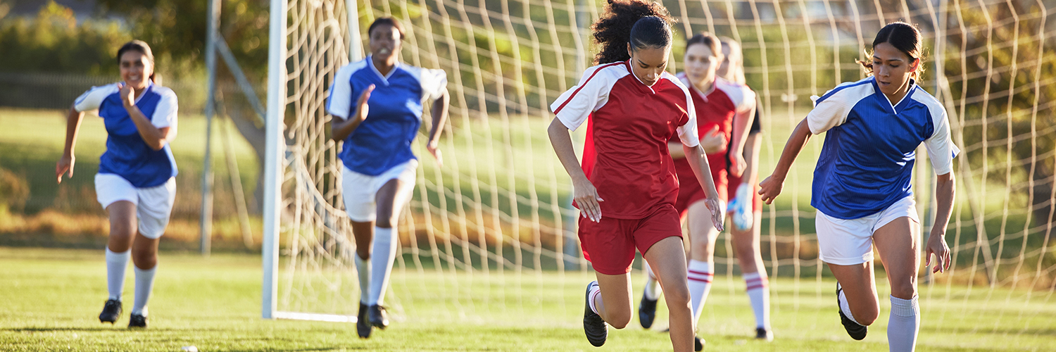 Sports team, girl soccer and kick ball on field in a tournament.