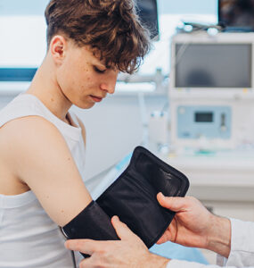 A teenage boy having his blood pressure checked by his pediatrician in a medical office.