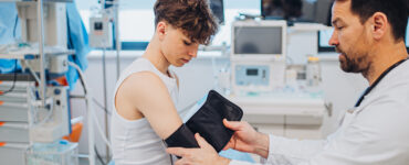 A teenage boy having his blood pressure checked by his pediatrician in a medical office.