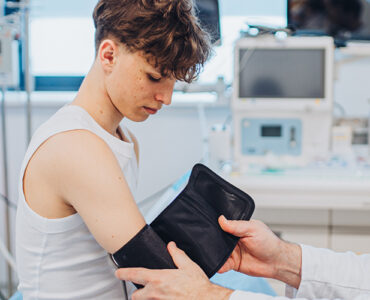A teenage boy having his blood pressure checked by his pediatrician in a medical office.