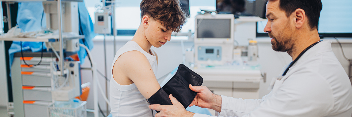 A teenage boy having his blood pressure checked by his pediatrician in a medical office.