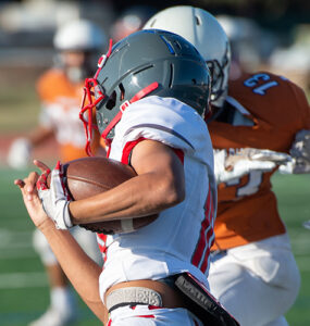 Three teenage football players running a play.