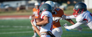 Three teenage football players running a play.