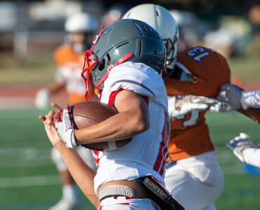 Three teenage football players running a play.