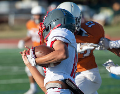 Three teenage football players running a play.