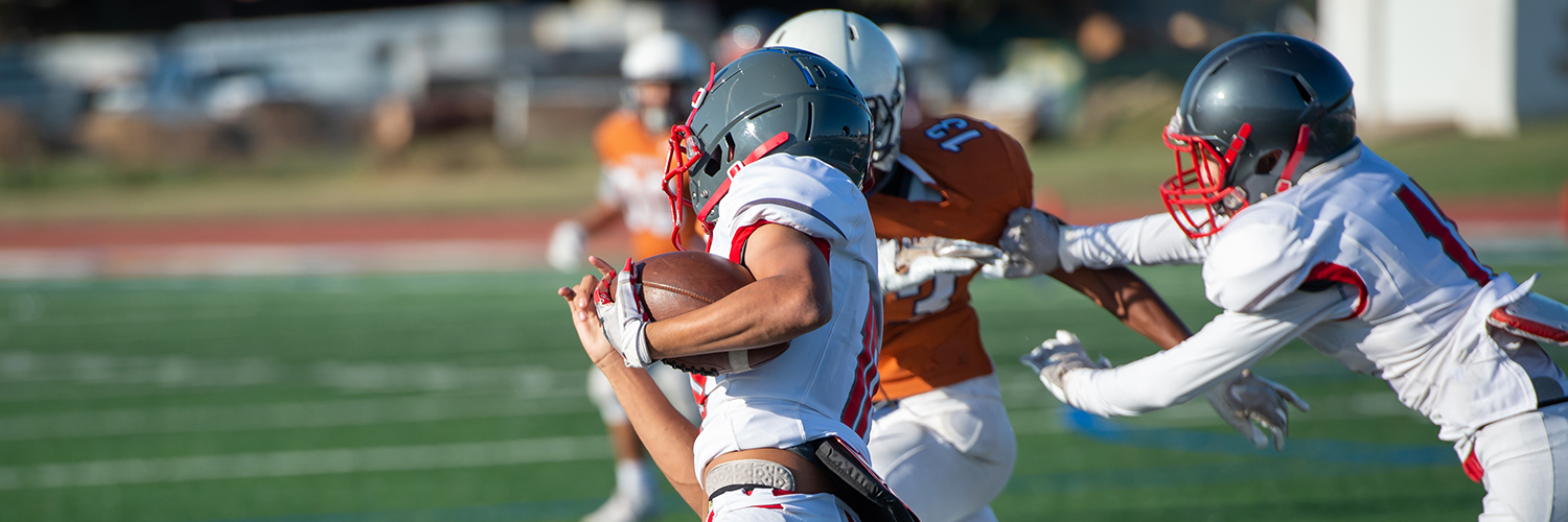 Three teenage football players running a play.