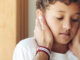 A young boy being consoled by his father while looking anxious.