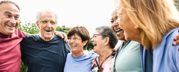 A group of adults ages 65 and up, standing together in a semi-circle and laughing.