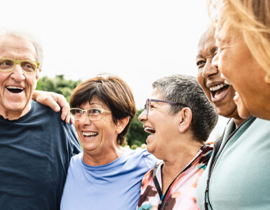 A group of adults ages 65 and up, standing together in a semi-circle and laughing.