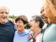 A group of adults ages 65 and up, standing together in a semi-circle and laughing.