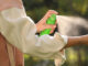 A woman spraying her arm with bug spray to prevent West Nile virus.