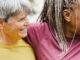 Four women over 50 of various ethnicities hugging together and smiling.